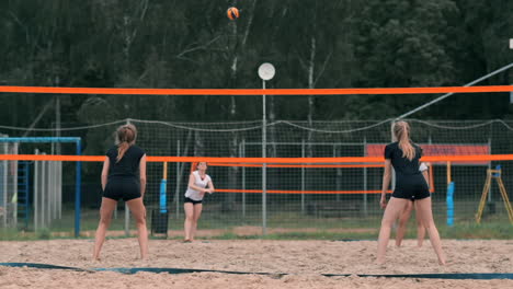 Young-woman-playing-volleyball-on-the-beach-in-a-team-carrying-out-an-attack-hitting-the-ball.-Girl-in-slow-motion-hits-the-ball-and-carry-out-an-attack-through-the-net.